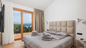 A bedroom with a large bed, a TV, a bedside table, and a view of the outdoors. - Villa 1 (Soline)
