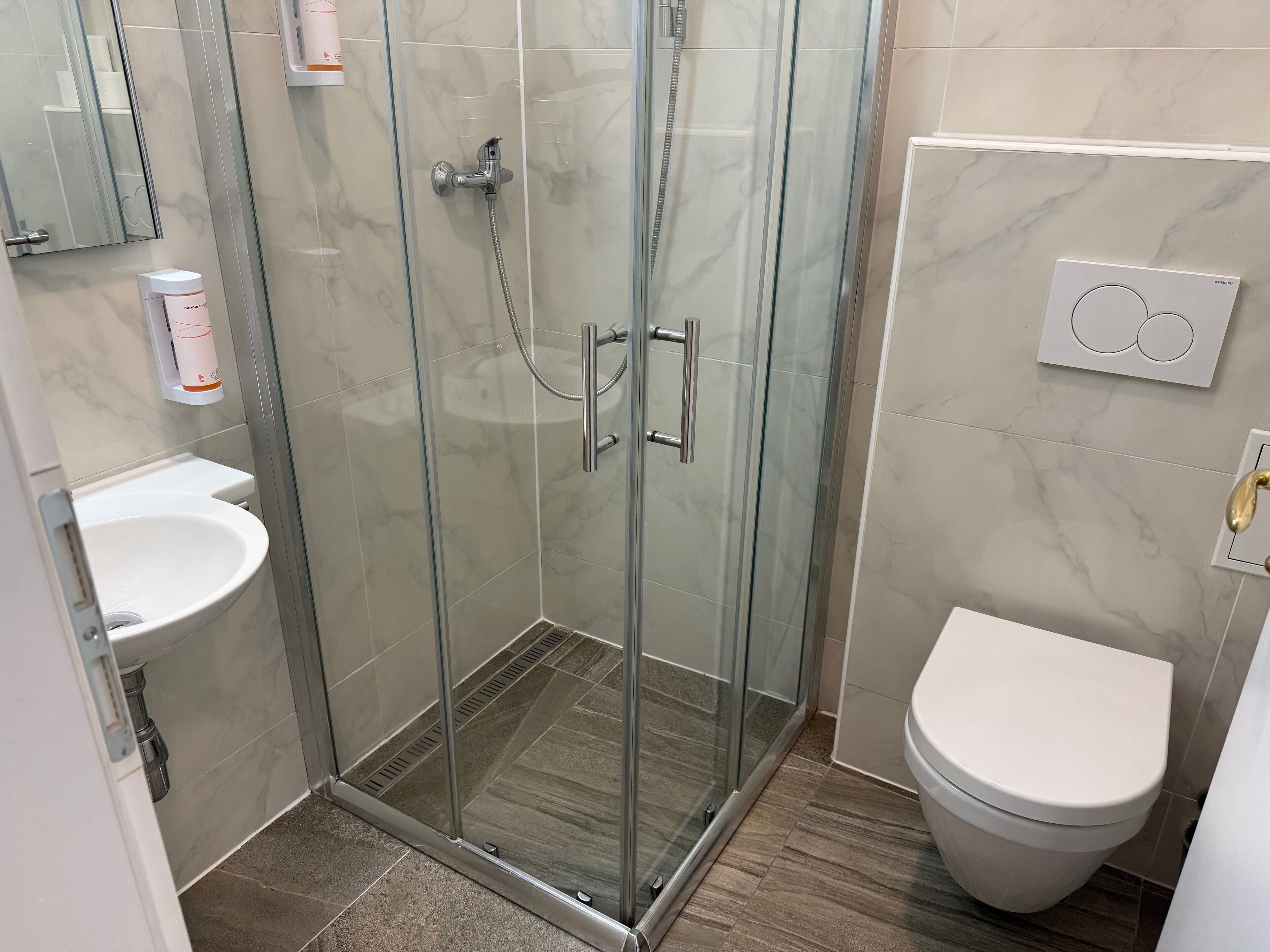 A modern bathroom with a glass-enclosed shower, a white sink, and a toilet.