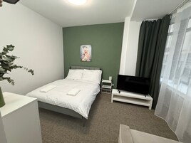 Habitación de hotel con cama, televisión, escritorio y planta.