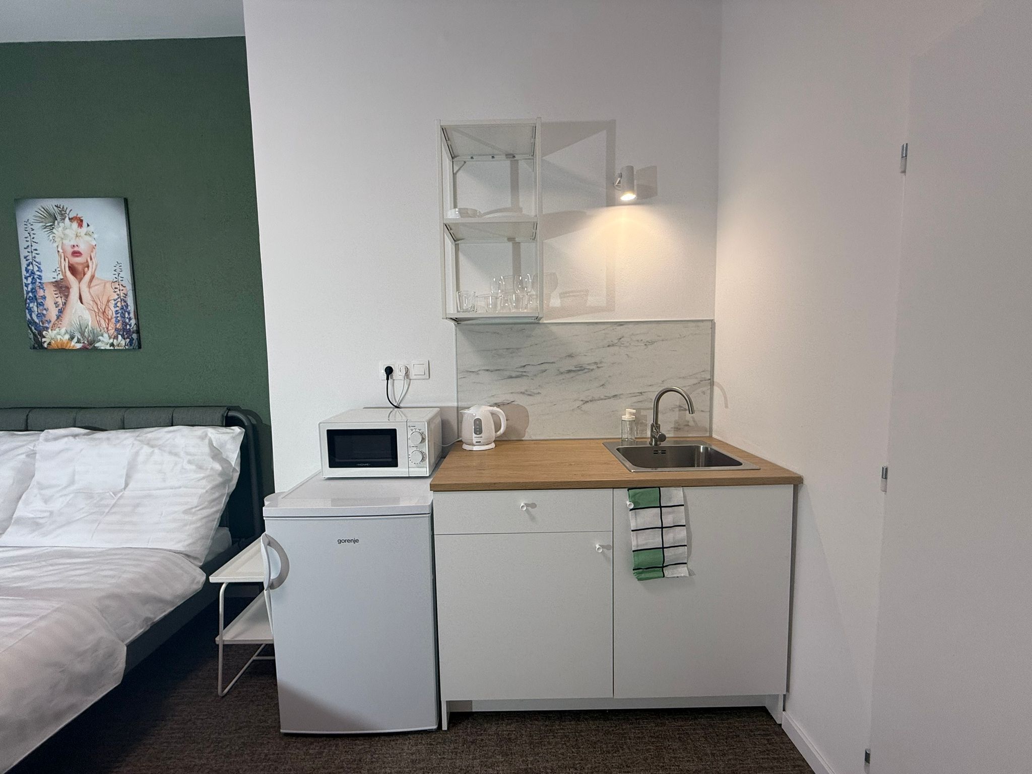 A compact kitchenette with a microwave, kettle, and sink.