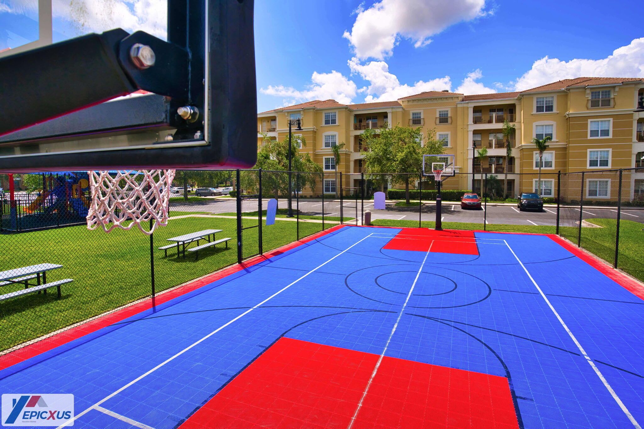 Un terrain de basket en plein air, équipé d’un panier, de bancs et d’une clôture.