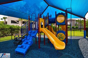 Un parque infantil con tobogán, estructuras para escalar y una zona cubierta.