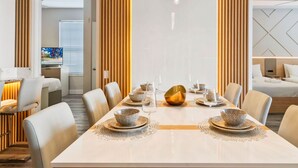 Un moderno comedor con una larga mesa dispuesta para seis personas, flanqueada por paneles de madera verticales y una araña.