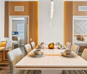 Un comedor moderno con una larga mesa dispuesta para seis personas, flanqueada por altos paneles de madera y una araña.
