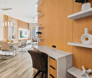 A modern interior with a wooden accent wall, a white desk, and a dining area with chairs and a table. - The Epic 00403 Vista Cay Resort Orlando Florida (Orlando)