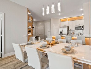 A modern kitchen with white cabinets, stainless steel appliances, and a dining area with a white table set for four.