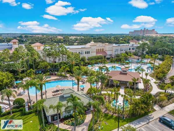 A resort with multiple swimming pools, palm trees, and a large building in the background.