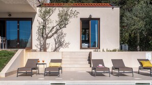 A modern building with a pool area, including lounge chairs and a small table with drinks. - Villa Casa Venus with pool in Istria, for 6 guests, quiet location, near Porec (Višnjan)