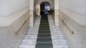 Eine Marmortreppe mit grünem Teppich, die zu einer Tür führt.
