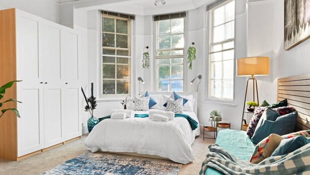 Un dormitorio con una cama grande, un escritorio y una ventana con vista a árboles.