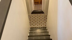 A staircase with a patterned floor and a wooden door at the top.