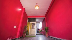 A corridor with red walls and a chandelier. There are potted plants along the sides. - Hotel Spark Inn || Near Motherhood Hospital (Noida)