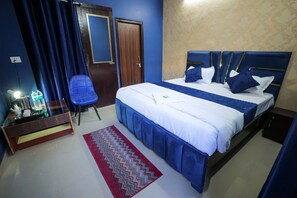 A hotel room with a bed, a desk with a lamp, a chair, and a red rug. - Hotel Spark Inn || Near Motherhood Hospital (Noida)