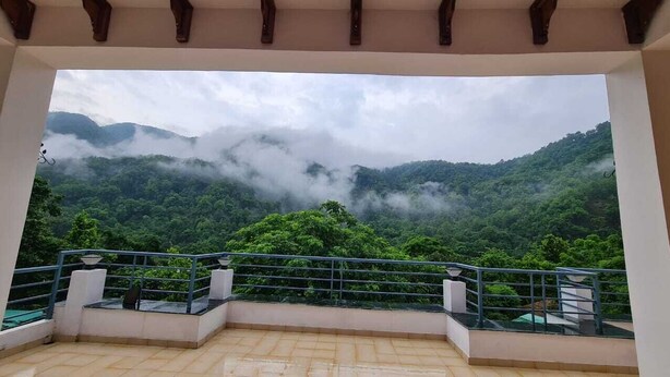 Un balcón con vistas a un valle verde exuberante y montañas envueltas en niebla.