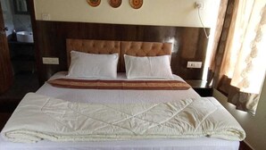 Una cama bien hecha con cubrecama acolchado, un cabecero de madera y una mesita de noche con una lámpara.
