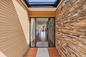 Un intérieur moderne agrémenté d’une verrière, de lambris en bois et d’un mur en pierre.