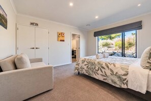 A bedroom with a bed, a sofa, a wardrobe, and a window with a view of the outdoors. - Cedar Sky | Tekapo 3BR | Near Mt John (Lake Tekapo)