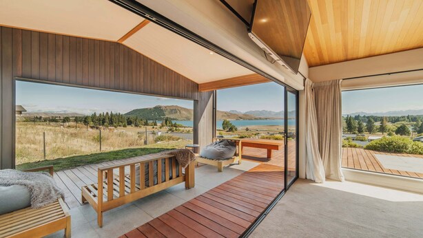 Un interior moderno con un ventanal grande que ofrece una vista panorámica de un lago y montañas.