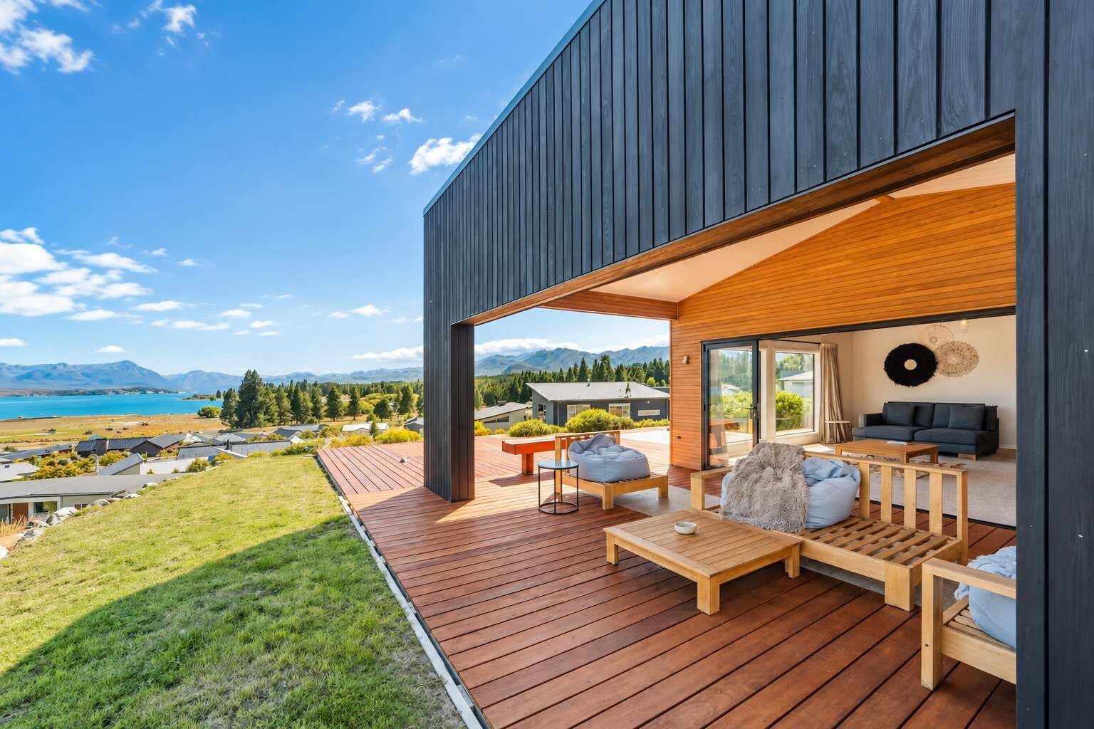 A modern house with a wooden deck, outdoor seating, and a scenic mountain view.