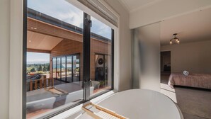 Un dormitorio moderno con un ventanal grande, una cama y vistas a una terraza y montañas.