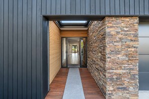 A modern hallway with a wooden floor, a stone wall, and a skylight. - Cedar Sky | Tekapo 3BR | Near Mt John (Lake Tekapo)
