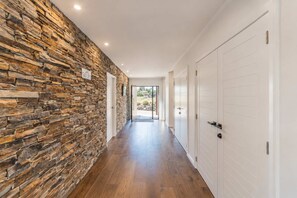 A hallway with a stone wall, wooden flooring, and white doors.
