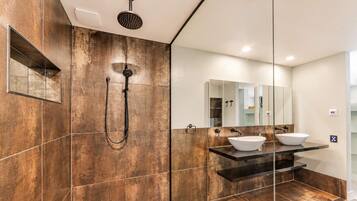 A modern bathroom with a large mirror, two sinks, and a shower.