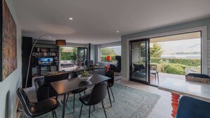 A modern dining area with a large table, black chairs, and a television in the background.