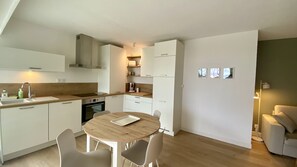 A compact kitchen with a sink, stove, and a dining area with a table and chairs. - Apartment for 4 people sea view with parking (Canet-en-Roussillon)