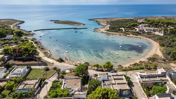 A coastal village with clear waters, boats, and traditional buildings.