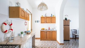 A kitchen with wooden cabinets, a gas stove, patterned floor tiles, and a life preserver on the wall.