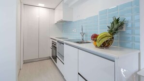 A modern kitchen with white cabinets, a stainless steel sink, and a fruit bowl on the counter.