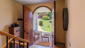 A hallway leading to a patio with a view of a garden.