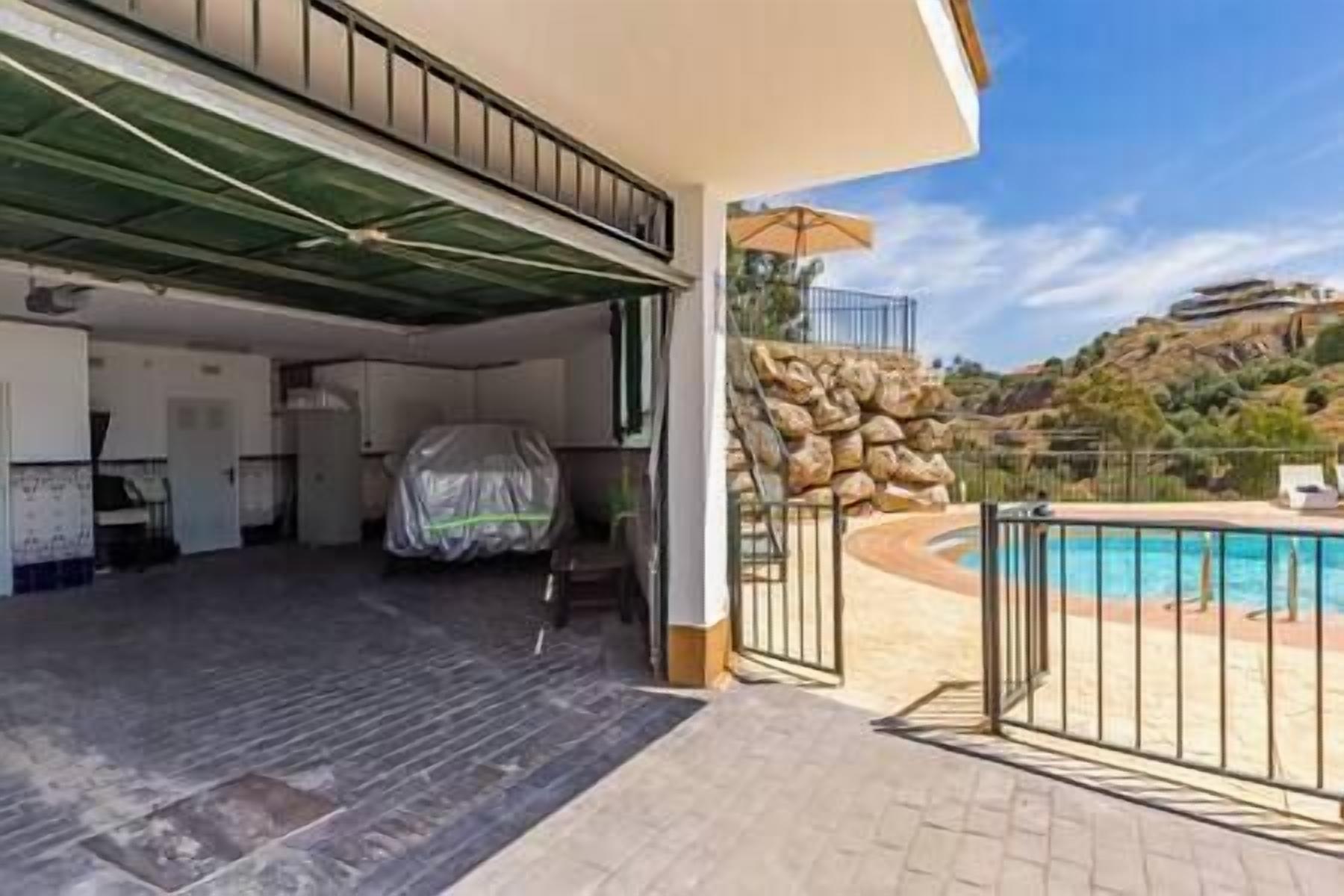 Un espacio al aire libre cubierto con piscina, un muro de piedra y vistas a un paisaje montañoso.