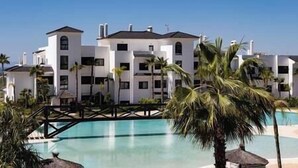 A resort with multiple white buildings, a swimming pool, and palm trees. - 2 Bedroom Apartment @Estepona Hills With Sea View! (Estepona)
