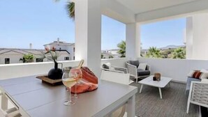 A modern balcony with a white table, a glass of white wine, and a decorative vase. - Brand New Gorgeous 2 Bed Property @ Estepona Hills (Estepona)