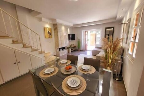 A modern dining area with a glass table, multiple chairs, and a decorative centerpiece.