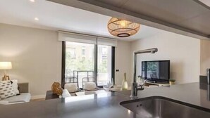 Eine moderne Küche mit einer großen Spüle, einem Essbereich mit Stühlen, einem Fernseher und einem großen Fenster.