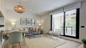 Ein modernes Wohnzimmer mit Essbereich, großen Fenstern und einem Balkon.