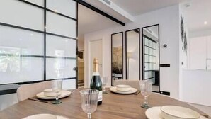 A dining area with a wooden table set for four, including plates, glasses, and a bottle of champagne.