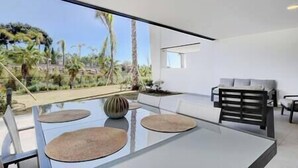 A modern dining area with a glass table, three woven placemats, and a minimalist bench.