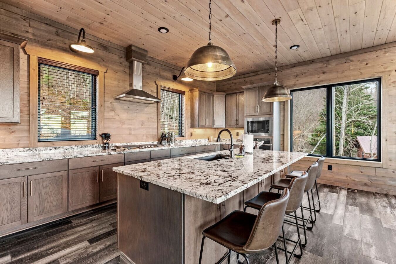 Une cuisine moderne dotée d’un grand îlot central, de meubles en bois et offrant une vue sur l’extérieur.