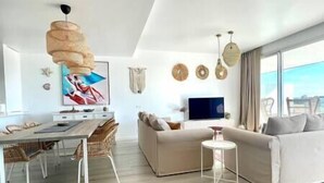 A modern living room with a sofa, a dining table, and a TV. - Stunning Three Bedroom Townhouse (Estepona)