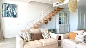A modern living room with a sofa, a coffee table, and a staircase. - Stunning Three Bedroom Townhouse (Estepona)