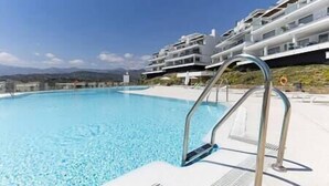 A swimming pool with a clear blue water, surrounded by a white building with balconies. - Stunning Three Bedroom Townhouse (Estepona)