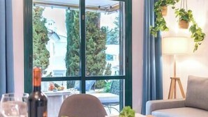Un coin repas avec une table dressée pour deux personnes, une bouteille de vin et une variété de légumes frais.