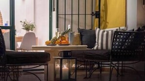 Un salon chaleureux avec un canapé, une table à manger agrémentée de fruits et d’un verre, et une table éclairée à la bougie.