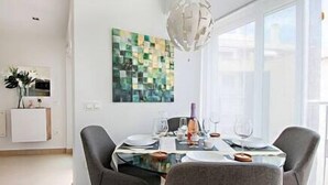 Ein stilvoller Essbereich mit einem Glastisch, grauen Stühlen und einem zeitgenössischen Kunstwerk an der Wand.