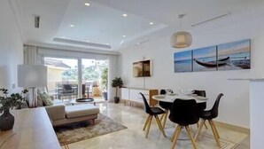 Uma área de refeições moderna com mesa e cadeiras, um sofá e uma janela grande com vista para o exterior.