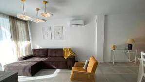 A living room with a sectional sofa, a wooden armchair, a small table with a lamp, and a ceiling fan.